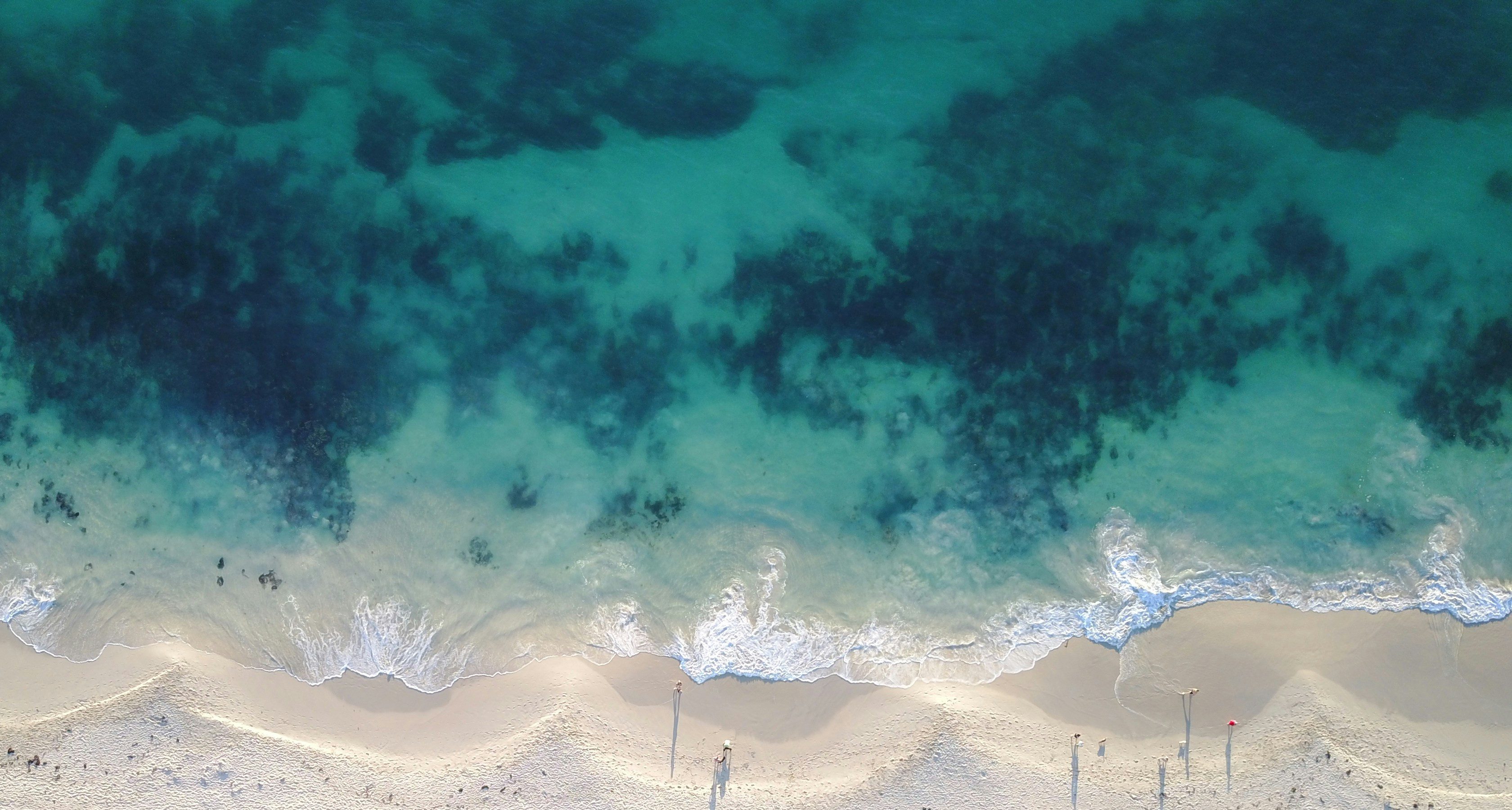 Aerial view of clear turquoise water meeting a long sandy beach
