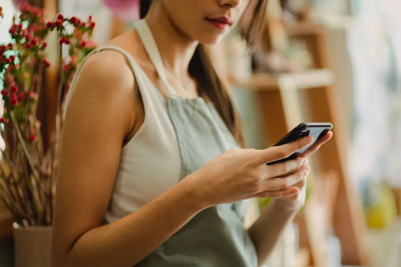 Small business owner checking her phone in her flower shop