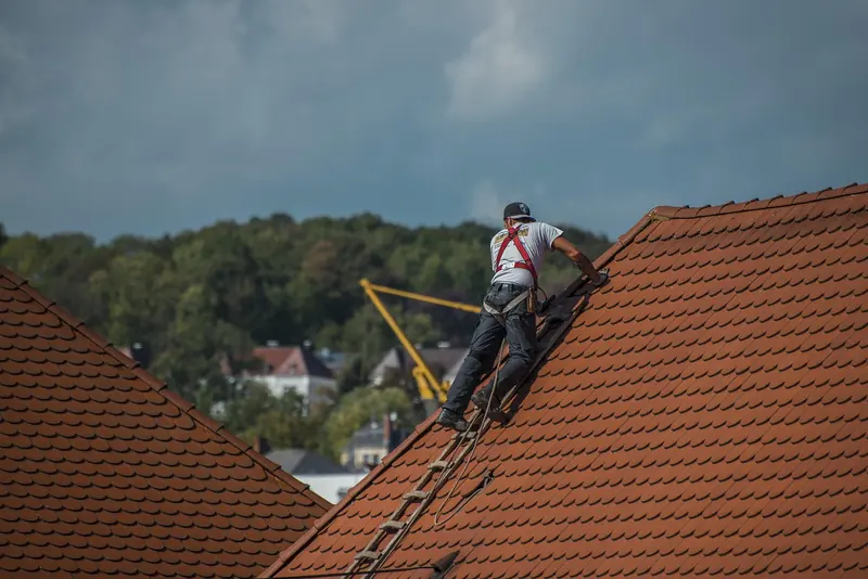 A roof tiler at work on a terracotta tiled roof