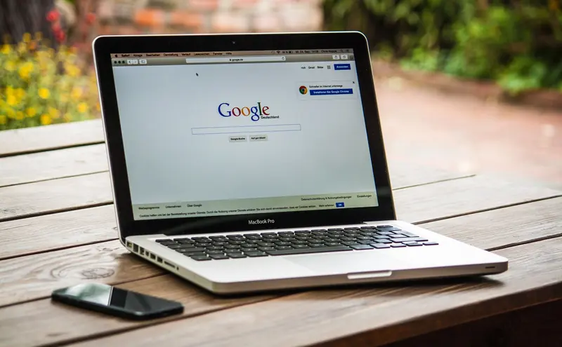 MacBook on a wooden table showing Google search